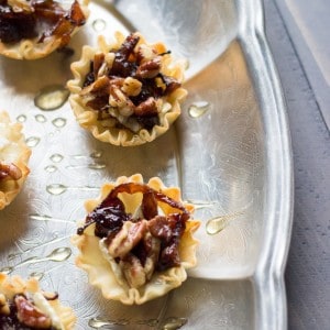 Baked brie cups topped with sweet caramelized onions, spicy nuts and a drizzle of honey! A simple, but pleaseing appetizer! www.lemonsforlulu.com #PantryInsider