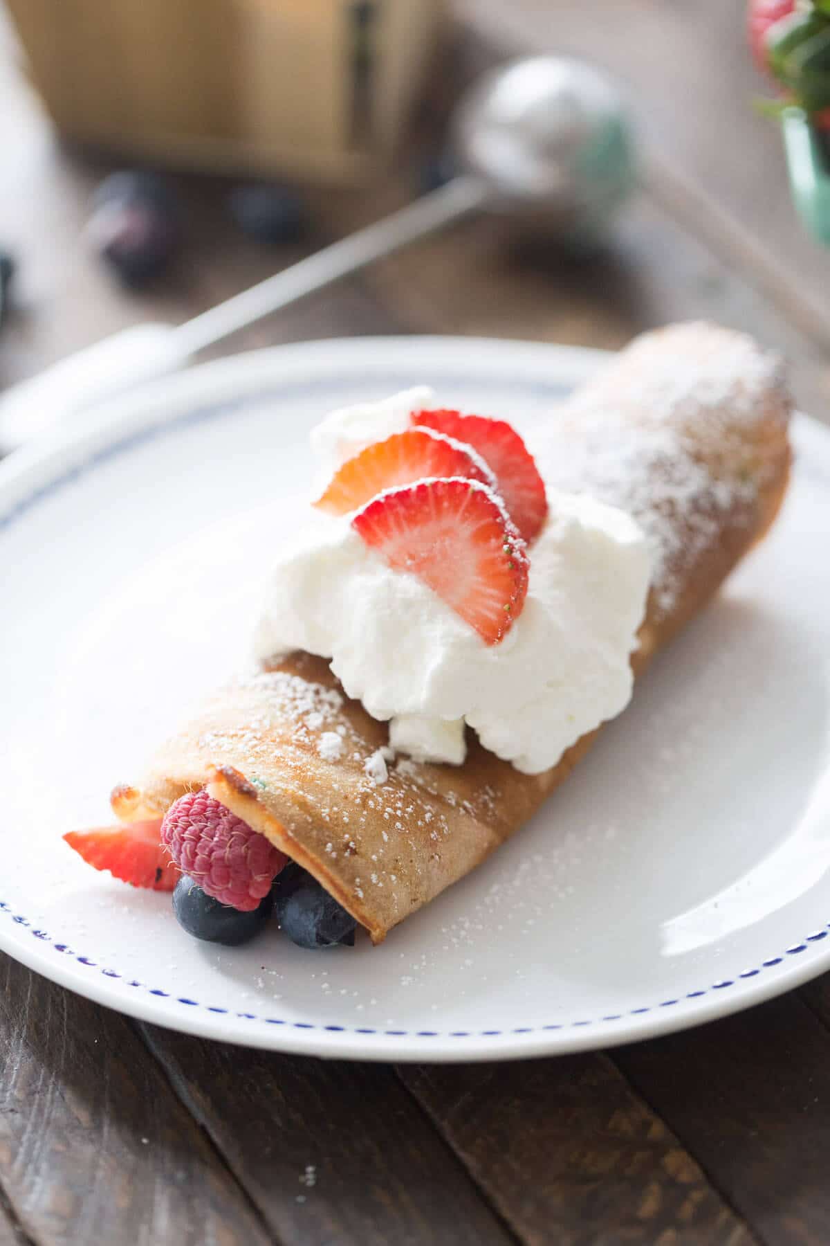 Red, White, & Blue Dessert Crepes on a white plate with fresh fruits.