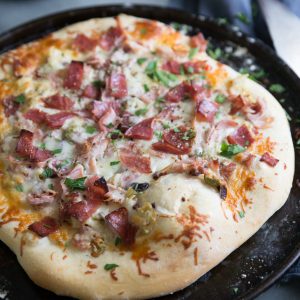 Muffaletta sandwich pizza on baking sheet