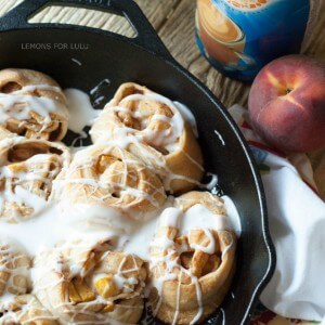 This cinnamon roll recipe is so easy, you will fall in love! A cast iron skillet, fresh peaches and crescent roll dough makes them irresistible! www.lemonsforlulu.com