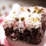 Chocolate poke cake filled with a cherry syrup and chocolate then topped with a creamy cherry topping! Pistachio nuts are sprinkled over top. lemonsforlulu.com