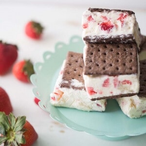 A homemade strawberry ice cream recipe spread between two chocolate graham crackers for a fun take on ice cream sandwiches! lemonsforlulu.com