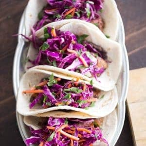 Grilled steak tacos have a fusion flair! Ginger infused cabbage and garlic beans make these tacos full of flavor!
