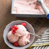 Chocolate swirled raspberry ice cream with raspberries in a small grey bowl.