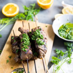 Beef shish kabobs with chimichurri sauce on beef and on the side